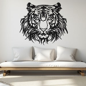 May include: Black and white silhouette of a tiger's face on a white wall, with a white couch in the foreground.