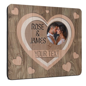 Puede incluir: Marco de fotos cuadrado de madera con un recorte en forma de coraz&oacute;n. El marco presenta un patr&oacute;n de vetas de madera e incluye los nombres "ROSE & JAMES" y espacio para "YOUR TEXT". Se ve una foto de una pareja.