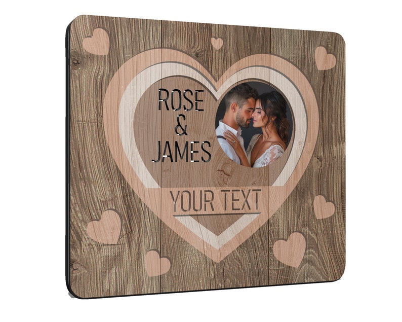 Puede incluir: Marco de fotos cuadrado de madera con un recorte en forma de coraz&oacute;n. El marco presenta un patr&oacute;n de vetas de madera e incluye los nombres "ROSE & JAMES" y espacio para "YOUR TEXT". Se ve una foto de una pareja.