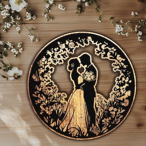 Puede incluir: Una decoración de pared circular de madera con una silueta de una pareja besándose rodeada de diseños florales.