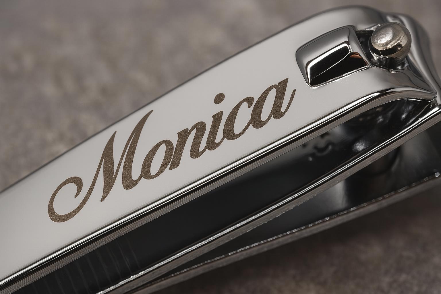 Close-up of a chrome nail clipper engraved with the name 'Monica'.