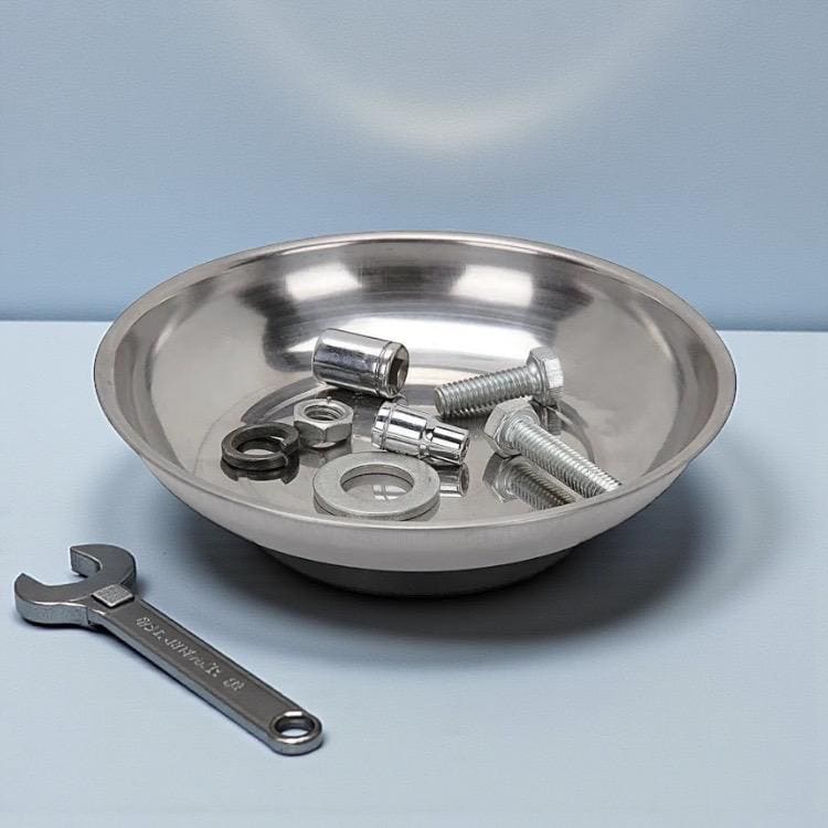 A metallic bowl containing miscellaneous hardware, with a small wrench resting beside it on a blue surface.