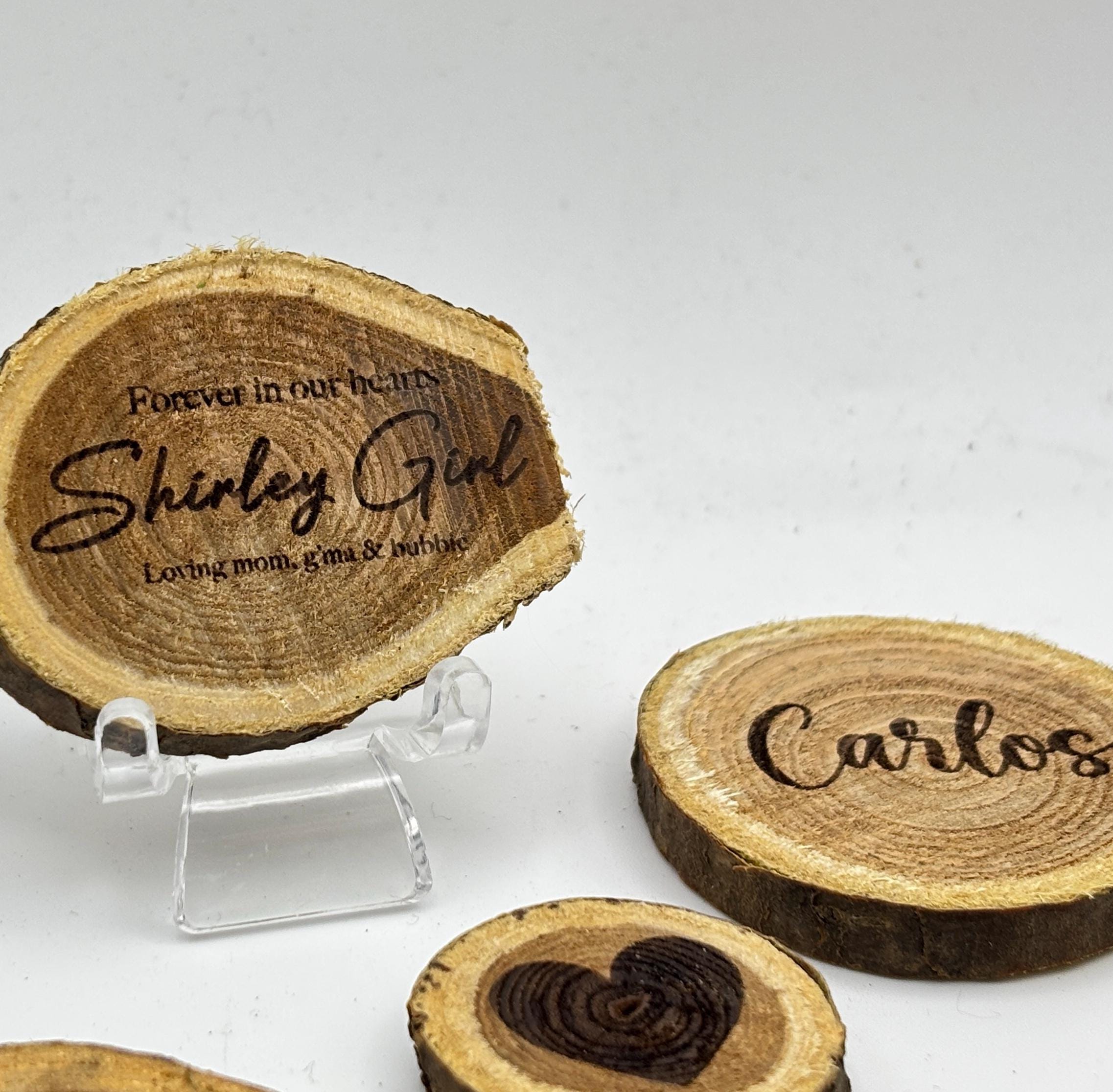 A close-up of a personalized wood slice on a small display stand next to other engraved wood pieces.