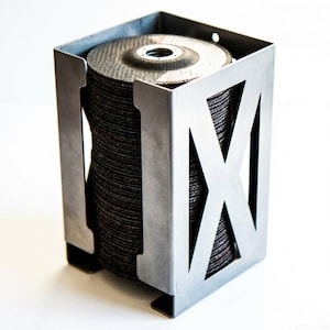 Puede incluir: Una pila de discos abrasivos de color gris oscuro se guarda en un soporte metálico plateado hecho a medida. El soporte tiene un diseño en forma de X en los laterales y una forma rectangular. Los discos están apilados ordenadamente dentro.
