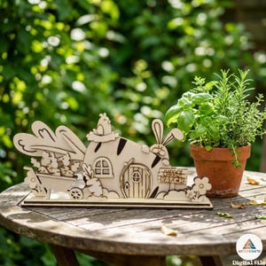 May include: A wooden Easter-themed decoration featuring a bunny house with a carrot patch sign. The house has a door, windows, and a bunny with long ears. A wheelbarrow with carrots and a potted plant are also present.