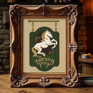 May include: A framed cross-stitch depicting a white horse on a green sign that reads "The Prancing Pony." The wooden frame is intricately carved. The image is set on a wooden table, with a stone fireplace and candles in the background.