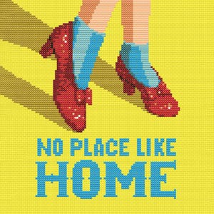 May include: Cross-stitch design featuring ruby red slippers with blue socks, set against a yellow background. The text "NO PLACE LIKE HOME" is displayed in blue. The image has a pixelated, handmade aesthetic.