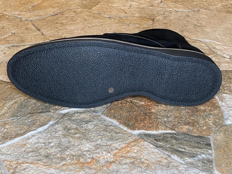 May include: Black suede shoe with a textured rubber sole. The shoe has a low profile and a gold-colored trim. The sole is marked with the number 10. The shoe is designed for comfort and style.