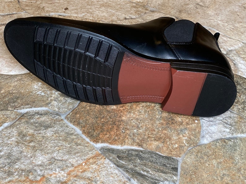 Puede incluir: Bota Chelsea de cuero negro con suela marr&oacute;n y suela exterior de goma negra. La suela tiene un patr&oacute;n texturizado para agarre. La bota incluye un panel lateral el&aacute;stico. Una opci&oacute;n de calzado cl&aacute;sica y vers&aacute;til.