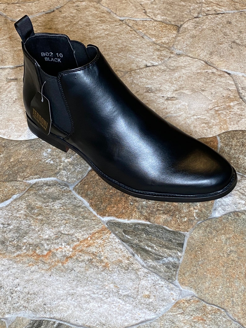Puede incluir: Bota Chelsea de cuero negro con punta redondeada. La bota tiene una leng&uuml;eta en la parte trasera y paneles laterales el&aacute;sticos. La etiqueta dice "TERRONI". Talla 10.