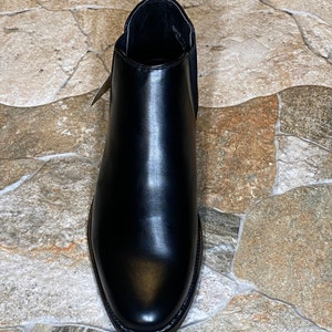 Puede incluir: Una bota Chelsea de cuero negro. La bota tiene una puntera redondeada, paneles laterales el&aacute;sticos y una leng&uuml;eta en la parte trasera. El cuero tiene un acabado pulido. La bota est&aacute; dise&ntilde;ada para el uso diario.