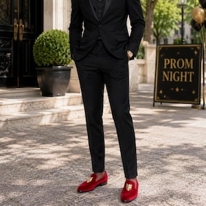 May include: A person in a black suit and red velvet loafers with gold accents. The sign in the background reads "PROM NIGHT". The outfit is formal and suitable for a special occasion.