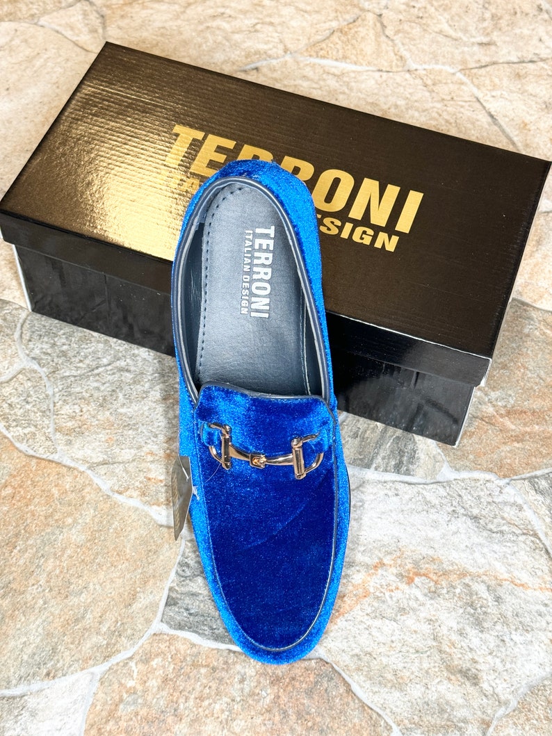 Puede incluir: Mocas&iacute;n de terciopelo azul con hebilla dorada, presentado con su caja negra. La caja tiene letras doradas que dicen "TERRONI ITALIAN DESIGN". El zapato tiene una plantilla de cuero con el nombre de la marca.