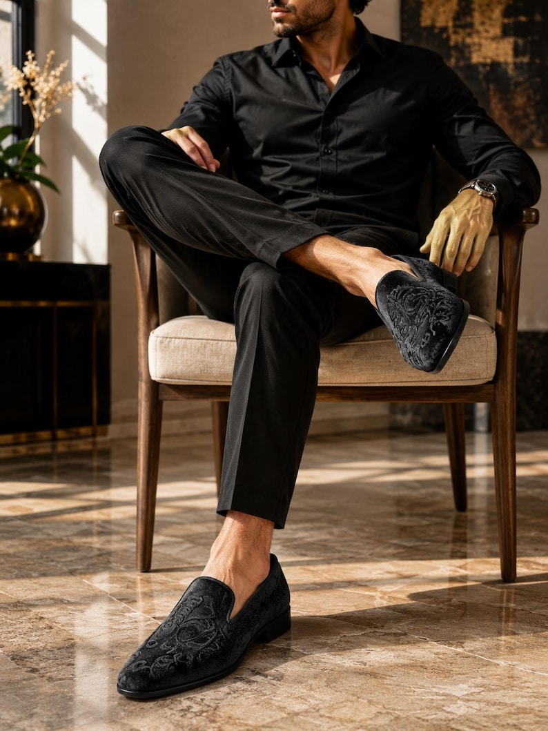 Puede incluir: Mocasines negros de terciopelo con un dise&ntilde;o floral bordado. Estos zapatos sin cordones tienen un tac&oacute;n bajo y una puntera redondeada. Los zapatos son parte de una colecci&oacute;n de ropa formal.