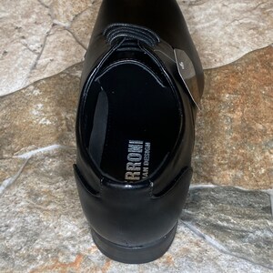 May include: A black leather dress shoe with a pointed toe and lace-up closure. The shoe has a smooth, polished finish and a small tag attached. The interior of the shoe has the text "RRONI ITALIAN DESIGN".
