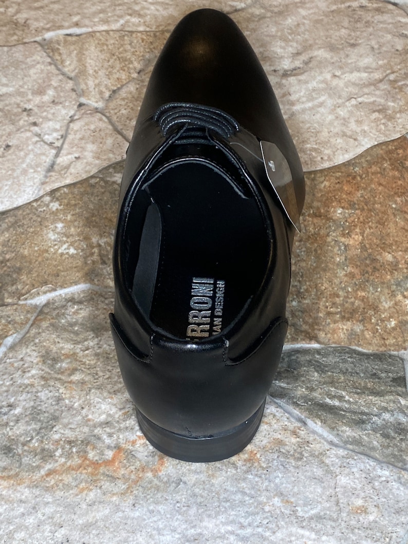 May include: A black leather dress shoe with a pointed toe and lace-up closure. The shoe has a smooth, polished finish and a small tag attached. The interior of the shoe has the text "RRONI ITALIAN DESIGN".