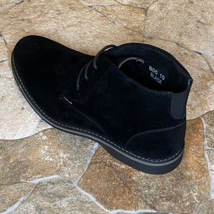 May include: Black suede chukka boot with a rounded toe and a gray sole. The boot has a lace-up closure and an elastic panel at the ankle. The text "B05 10 Black" is visible inside the boot.