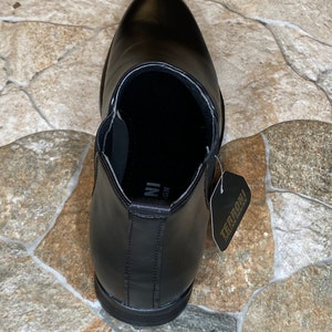 Puede incluir: Bota Chelsea de cuero negro con punta afilada. La bota tiene una leng&uuml;eta y paneles laterales el&aacute;sticos. Una etiqueta con "TERRONI ITALIA DESIGN" est&aacute; adjunta.