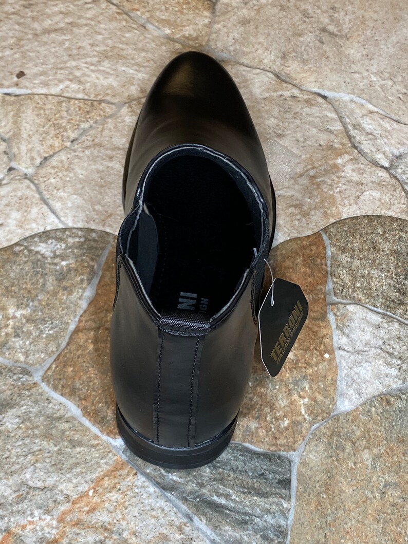 Puede incluir: Bota Chelsea de cuero negro con punta afilada. La bota tiene una leng&uuml;eta y paneles laterales el&aacute;sticos. Una etiqueta con "TERRONI ITALIA DESIGN" est&aacute; adjunta.