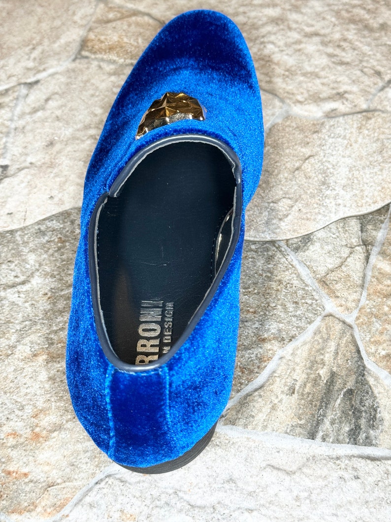 May include: A single, royal blue velvet loafer with a gold-colored geometric embellishment. The shoe has a black sole and trim. The brand name "BRROW" is visible on the insole. The shoe is a size 10.