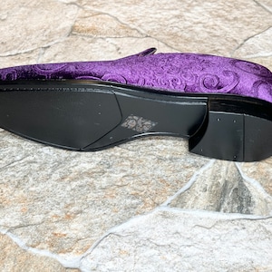 Op de afbeelding: Een paarse fluwelen loafer met een decoratief patroon. De schoen heeft een zwarte zool en hak. De schoen is ongeveer 28 cm lang.