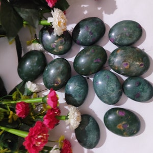 May include: A collection of 12 green and pink tumbled stones. The stones are oval shaped and have a smooth, polished finish.