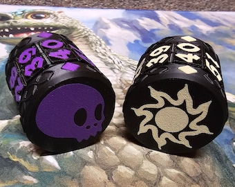 May include: Two black dice with different symbols on each side. One die has a purple skull and the other has a white sun. Both dice have numbers 35, 39, 40, 45, 50, and 59 on the sides.