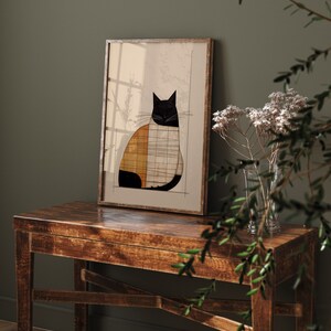 Pu&ograve; includere: Una stampa incorniciata di un'illustrazione geometrica di un gatto nero, bianco e arancione. La stampa &egrave; appesa a un muro sopra un tavolo di legno.