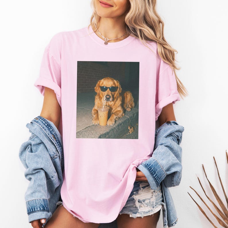 Golden retriever wearing sunglasses holds iced coffee in its mouth.