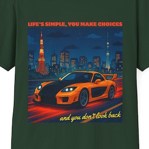 Op de afbeelding: Donkergroen t-shirt met een afbeelding van een oranje sportwagen die 's nachts racet, tegen een stadsgezicht. De tekst luidt "LIFE'S SIMPLE, YOU MAKE CHOICES" en "and you don't look back".