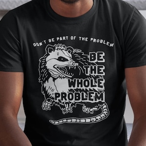 May include: Black t-shirt with a white graphic of a possum with the text "Don't be part of the problem, be the whole problem."