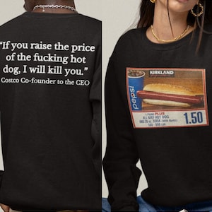 以下が含まれることがあります： 背中に「If you raise the price of the fucking hot dog, I will kill you.」と書かれた黒いスウェットシャツ。前面には、1.50ドルの価格が付いたカークランドのホットドッグとソーダのグラフィックがあります。