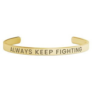 May include: Gold-toned metal bracelet with the inscription "ALWAYS KEEP FIGHTING".