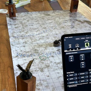 May include: A tabletop game setup with a gridded map, miniature figures, dice, and a tablet displaying a character sheet with stats and saving throws. The tablet screen shows the text "Saving Throws" and "Strength +5".