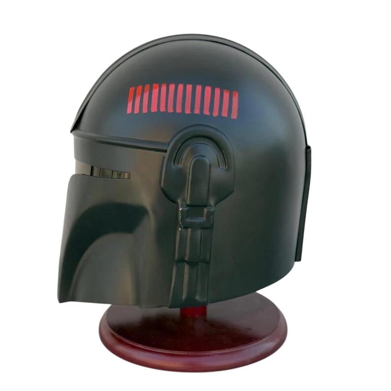 May include: A dark green helmet with a visor and a series of red rectangular lights on top. The helmet is displayed on a dark brown wooden stand. The helmet has a smooth, matte finish.