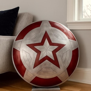 May include: A large, round shield with a red, white, and silver color scheme. The shield features a prominent five-pointed star in the center, surrounded by a circular design. It is displayed on a silver stand.