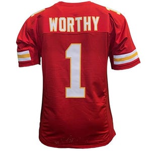 May include: Red football jersey with the name "WORTHY" and the number "1" in white and gold. The jersey has white and gold stripes on the sleeves and shoulders. The jersey is made of a mesh material.