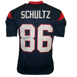 May include: Navy blue football jersey with the name "SCHULTZ" and the number "86" in white. The jersey has red accents on the shoulders and collar. A signature is visible on the number.