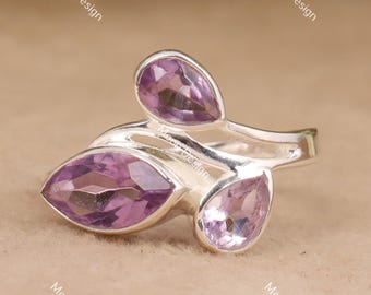 May include: A silver ring featuring three purple gemstones in a leaf-like design. The gemstones are pear and marquise-shaped, with a polished finish. The ring is set against a neutral background.