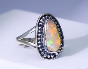 May include: A silver ring with a white opal gemstone set in a beaded oval bezel.