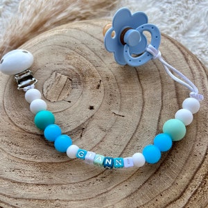 Personalized pacifier clip for baby in blue tones. small fluorescent blue beads, white thread