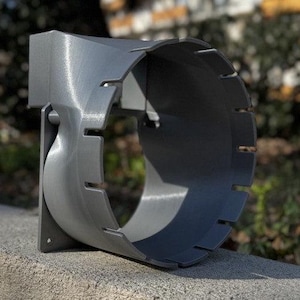 Könnte beinhalten: Ein grauer 3D-gedruckter Lüfterschutz mit einer strukturierten Oberfläche und einer Reihe von Schlitzen am Umfang.