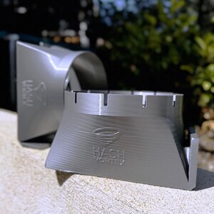 Puede incluir: Dos vórtices de hachís de plástico gris impresos en 3D. Los vórtices están diseñados para ayudar a hacer hachís. El vórtice más grande tiene las palabras "Hash Vortex" impresas en el lateral.
