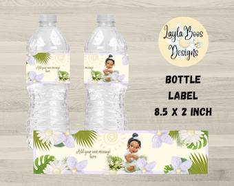 Puede incluir: Etiqueta para botella de agua con una ilustración de dibujos animados de una niña con piel morena y una corona, que lleva un vestido verde y sostiene una rana. La etiqueta tiene un tema tropical con hojas verdes, flores blancas y un sol amarillo. El texto "Añade tu propio mensaje aquí" está incluido en la etiqueta. La etiqueta mide 8,5 pulgadas por 2 pulgadas.