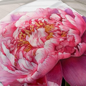 May include: A white fleece blanket with a large pink peony flower printed on it. The flower is in full bloom and has a delicate watercolor style.