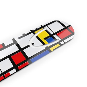 May include: A white metal bookmark with a geometric design in red, yellow, blue, and black. The bookmark has a cut-out shape for holding a page.