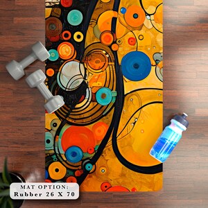 May include: Abstract yoga mat with a colorful design featuring circles, swirls, and lines in shades of yellow, orange, blue, and black. The text "MAT OPTION: Rubber 26 X 70" is printed on the bottom of the mat.