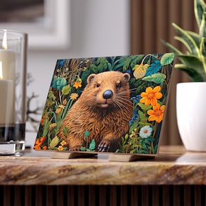 May include: A brown and tan beaver with a black nose and whiskers is peeking out from a lush green forest with colorful flowers. The beaver is looking directly at the viewer.