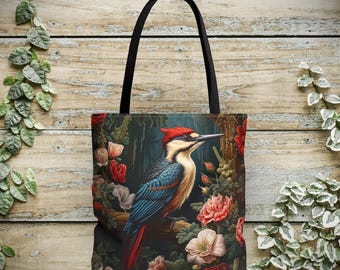 Könnte beinhalten: Eine schwarze Tragetasche mit einer farbenfrohen Illustration eines Spechts, der auf einem Ast mit Blumen sitzt. Der Vogel hat rote, blaue und weiße Federn, und die Blumen sind rosa, rot und weiß.