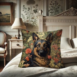May include: A decorative square pillow featuring a German Shepherd dog surrounded by red and pink flowers and green foliage. The dog has black and tan fur. The pillow is on a white bedspread.